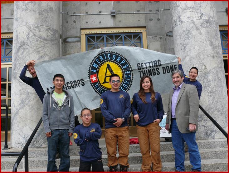 Sam stands with Alaska Service Corps- Summer Youth Crew -Russell King (Crew Leader- holding the sign), Avery Chiklak, Jerry Philip. Cody Kokrine. Kayla Williams and Jennifer Joe (Crew Leader- holding the sign)