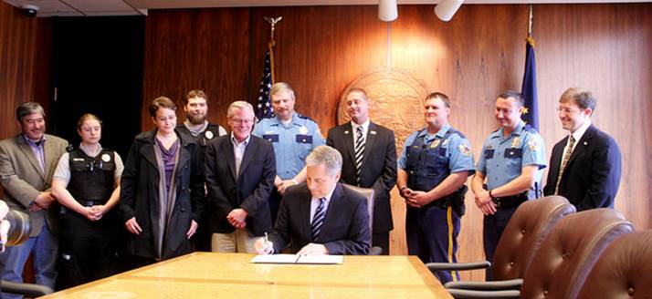 Sam with Senator Dennis Egan and local law enforcement at the signing of SB 116.