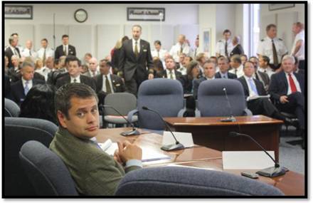 Representative Chris Tuck is caught by the camera just before the beginning of the packed-house hearing about impacts of UPS layoffs on Anchorage families and economy.