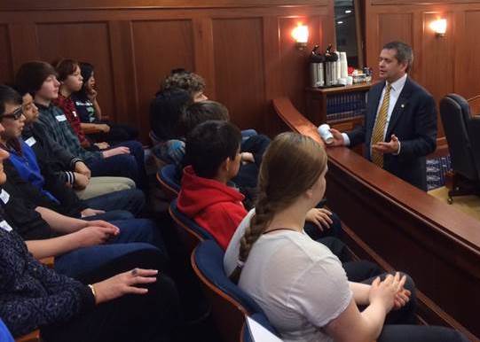 Rep. Chris Tuck chats with Juneau students visiting from Floyd Dryden Middle School who are seated in the Warren Taylor Gallery of the House Floor.